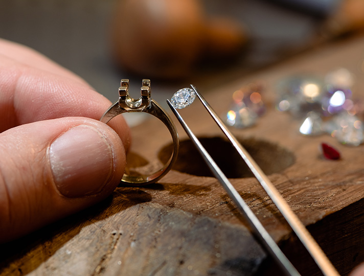 tweezers holding stone above ring setting